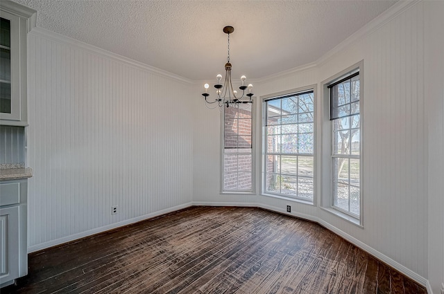 unfurnished dining area with dark wood-type flooring, crown molding, a textured ceiling, and a notable chandelier