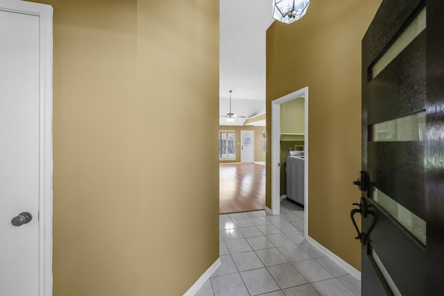 hallway featuring light tile patterned flooring, washer / clothes dryer, and vaulted ceiling