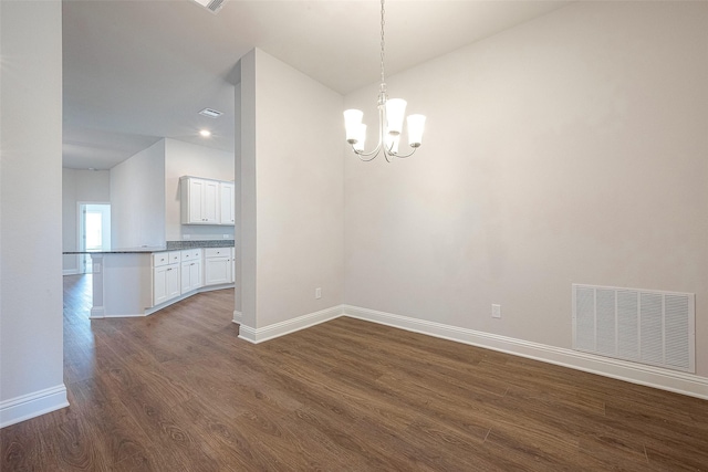 unfurnished dining area featuring dark wood-type flooring and an inviting chandelier