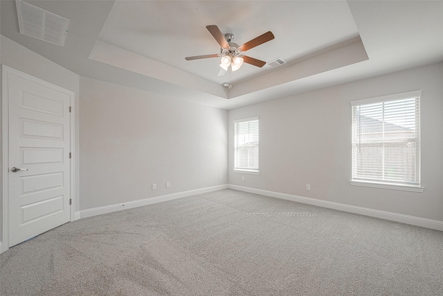 carpeted empty room featuring a raised ceiling and ceiling fan