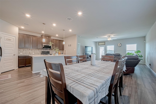 dining room with ceiling fan and light wood-type flooring