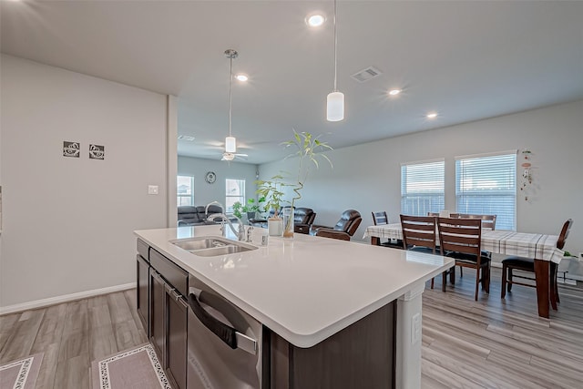 kitchen with a kitchen island with sink, sink, pendant lighting, and stainless steel dishwasher