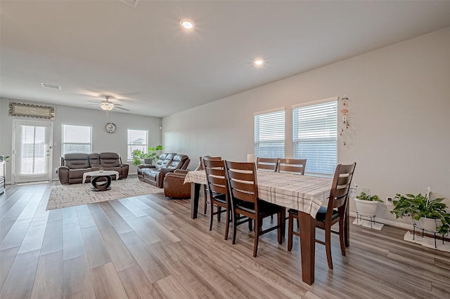 dining space with ceiling fan and light wood-type flooring