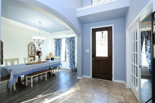 tiled entrance foyer with a tray ceiling and a chandelier