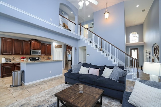 tiled living room with ceiling fan and a towering ceiling