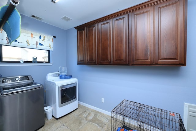 laundry area featuring light tile patterned flooring, cabinets, and washer and clothes dryer