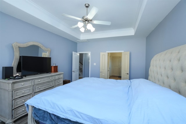 bedroom with crown molding, ceiling fan, and a tray ceiling