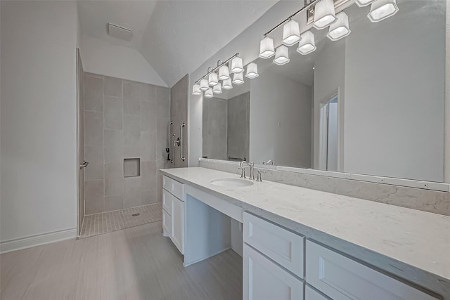 bathroom featuring a tile shower, vanity, and vaulted ceiling