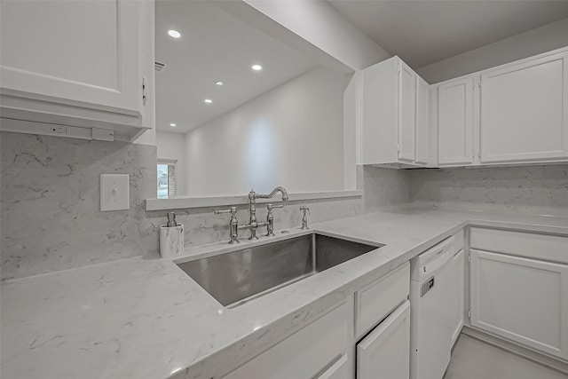 kitchen with sink, light stone counters, dishwasher, white cabinets, and backsplash