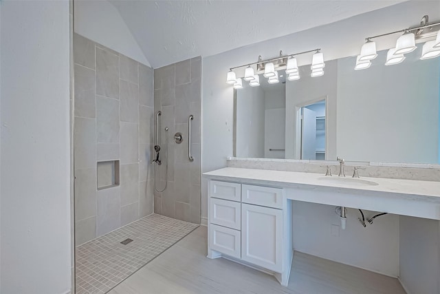 bathroom featuring vaulted ceiling, sink, and a tile shower