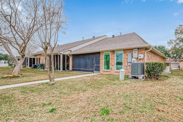 view of front of house with a front yard, a sunroom, and central air condition unit