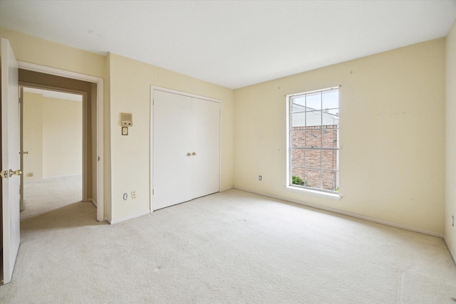 unfurnished bedroom featuring light carpet and a closet