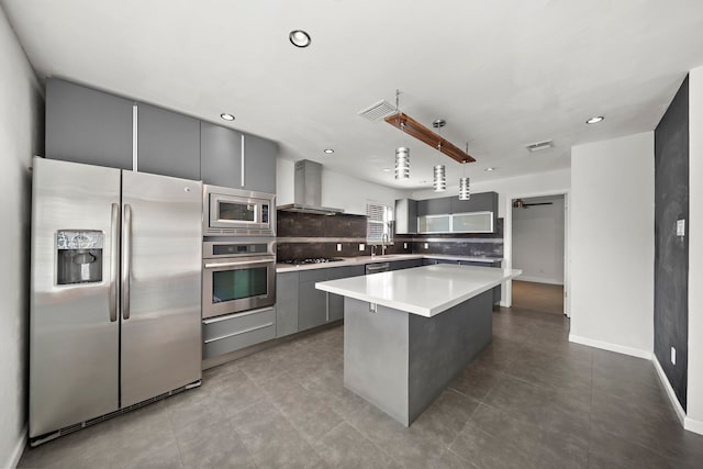 kitchen with gray cabinets, a center island, wall chimney exhaust hood, and appliances with stainless steel finishes