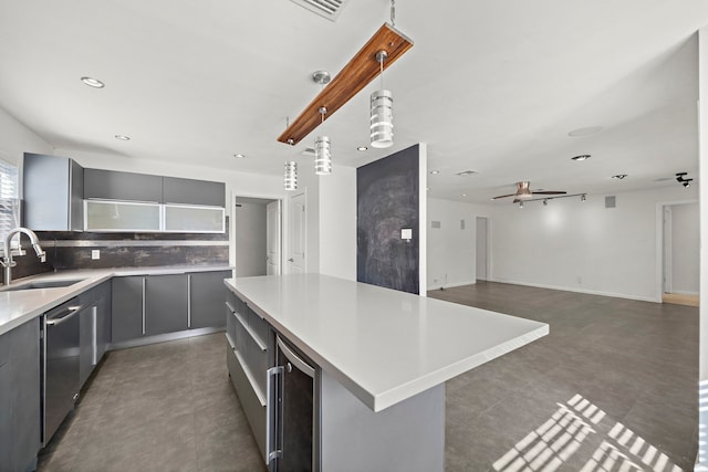 kitchen featuring sink, gray cabinets, hanging light fixtures, a kitchen island, and stainless steel dishwasher