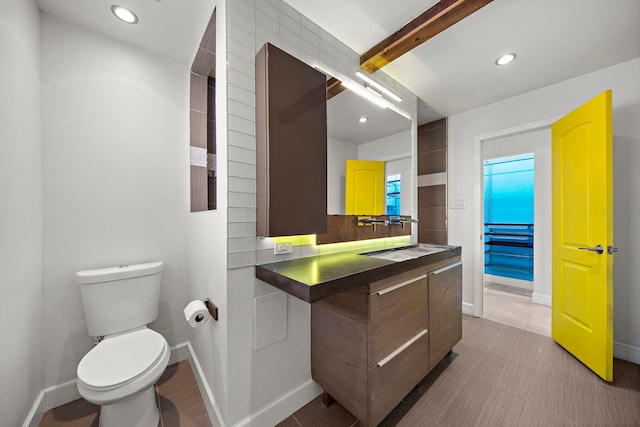 bathroom featuring beamed ceiling, vanity, and toilet