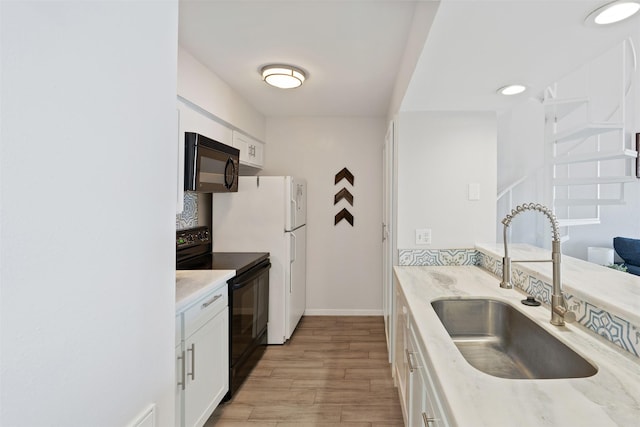 kitchen featuring white cabinetry, sink, light hardwood / wood-style flooring, and black appliances