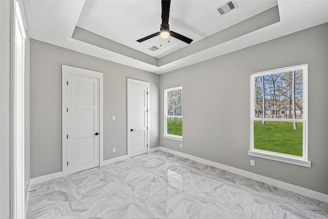 unfurnished bedroom featuring ceiling fan and a tray ceiling