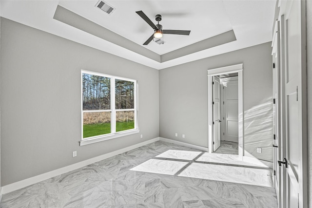 unfurnished bedroom featuring ceiling fan, a tray ceiling, and a closet