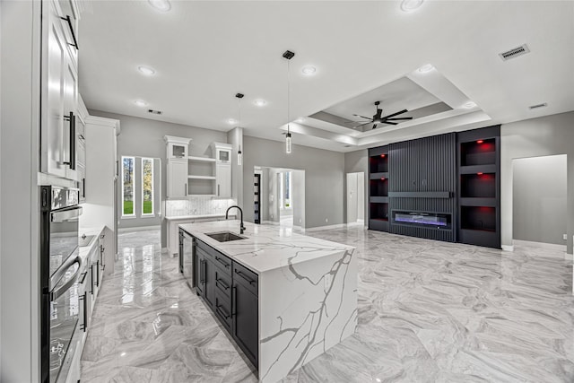 kitchen with white cabinetry, a tray ceiling, sink, and hanging light fixtures