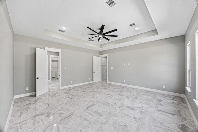 unfurnished bedroom featuring ceiling fan and a tray ceiling