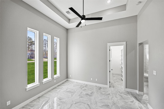 spare room featuring a raised ceiling and ceiling fan