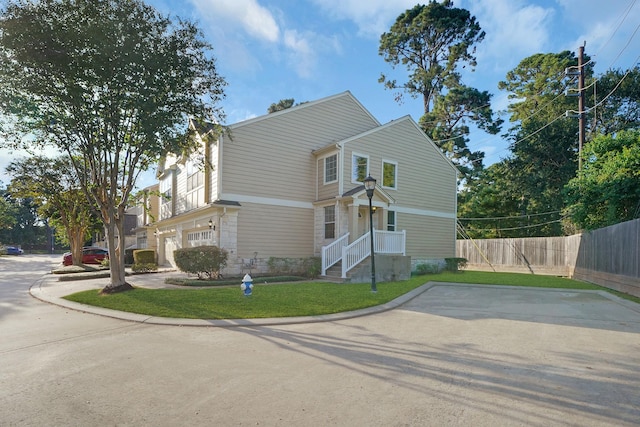 view of home's exterior with a lawn, concrete driveway, and fence