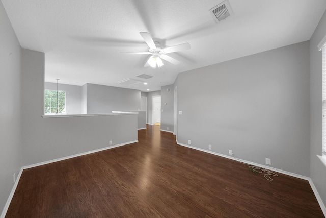 empty room featuring visible vents, baseboards, dark wood-type flooring, and a ceiling fan