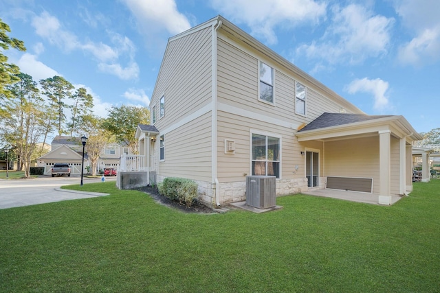 back of property featuring stone siding, a lawn, and central AC unit