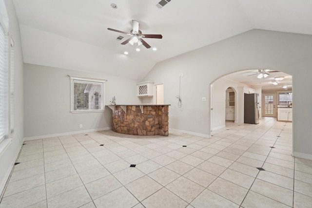 unfurnished living room featuring ceiling fan, a wealth of natural light, vaulted ceiling, and light tile patterned floors