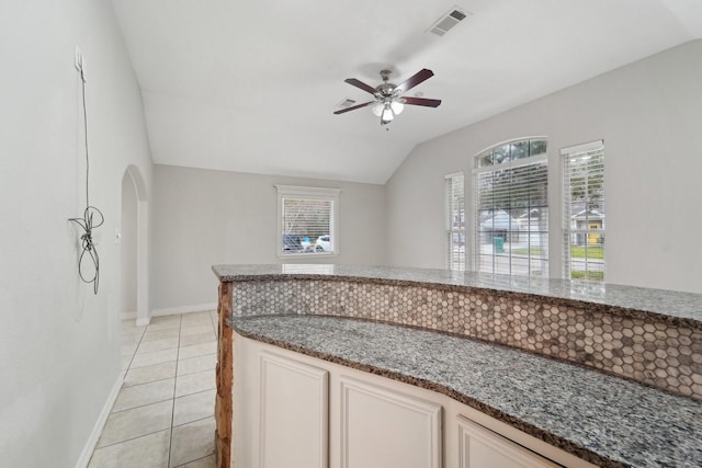 kitchen featuring lofted ceiling, light tile patterned floors, ceiling fan, and stone counters