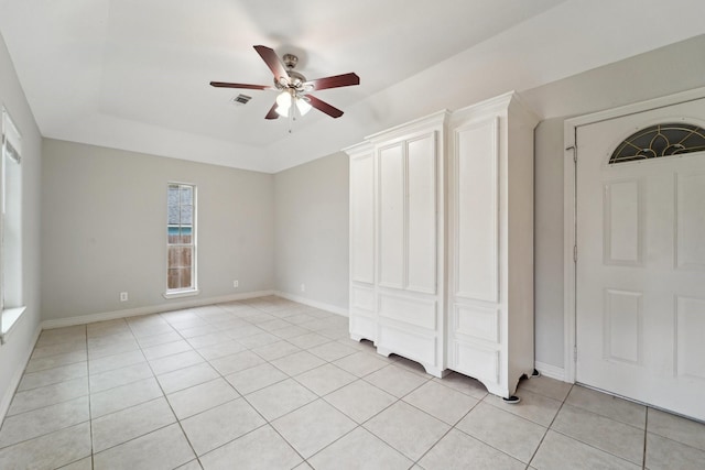 unfurnished bedroom featuring light tile patterned flooring, a closet, ceiling fan, and a tray ceiling