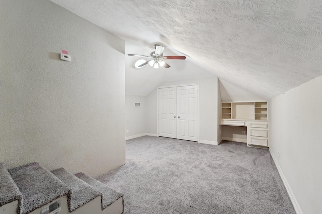 additional living space featuring lofted ceiling, ceiling fan, light carpet, and a textured ceiling