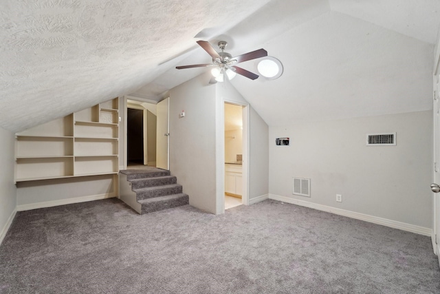 additional living space with lofted ceiling, built in features, a textured ceiling, and carpet flooring