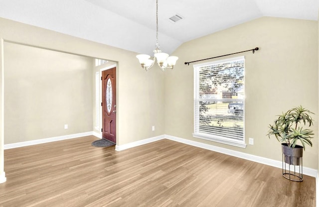 empty room with an inviting chandelier, wood-type flooring, and vaulted ceiling