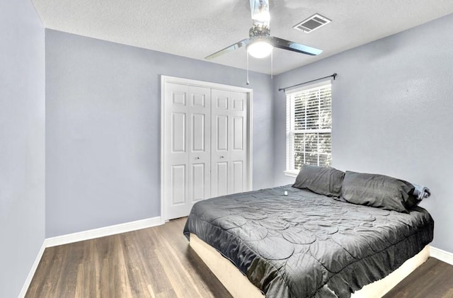 bedroom with hardwood / wood-style flooring, ceiling fan, a closet, and a textured ceiling