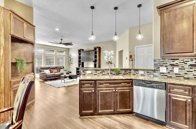 kitchen with sink, backsplash, hanging light fixtures, light stone countertops, and stainless steel dishwasher