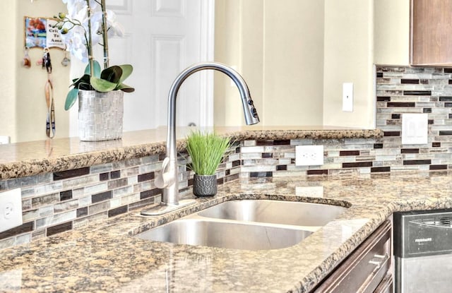 kitchen featuring tasteful backsplash, dishwasher, sink, and light stone counters