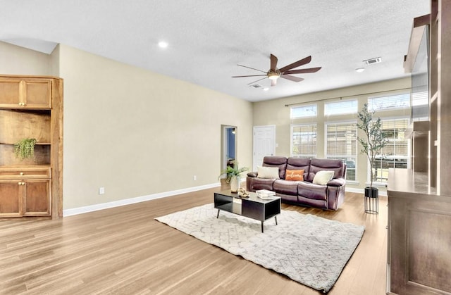 living room featuring ceiling fan, light hardwood / wood-style floors, and a textured ceiling