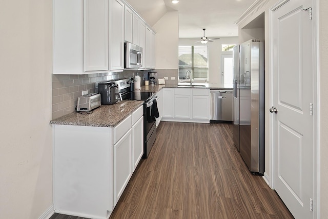 kitchen with sink, stone counters, stainless steel appliances, white cabinets, and decorative backsplash