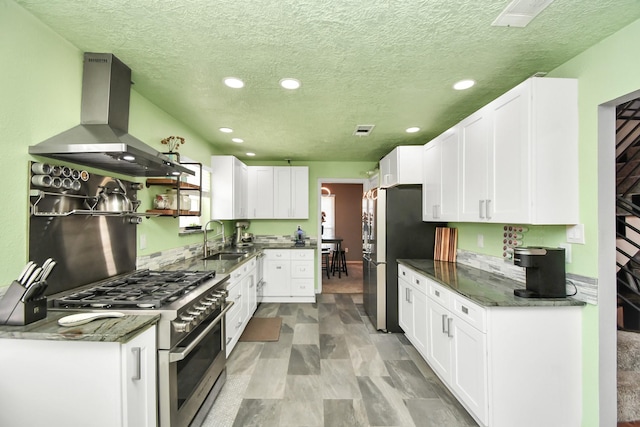 kitchen with white cabinetry, appliances with stainless steel finishes, dark stone countertops, and extractor fan