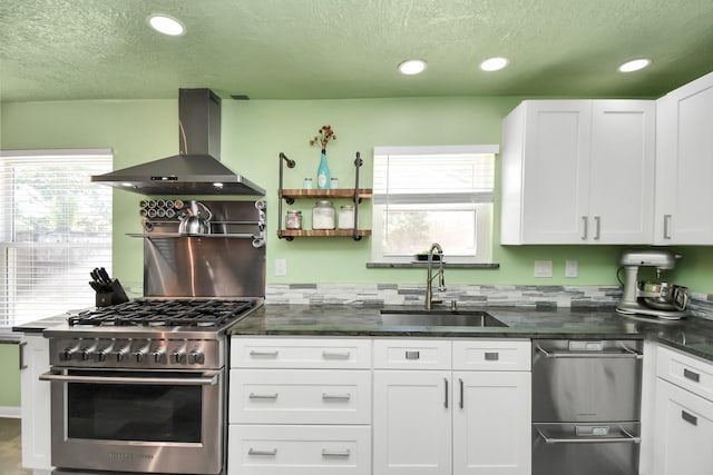 kitchen with white cabinetry, high end stove, sink, and wall chimney exhaust hood