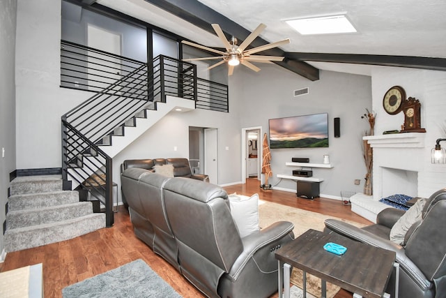 living room featuring hardwood / wood-style flooring, ceiling fan, a fireplace, and lofted ceiling with beams