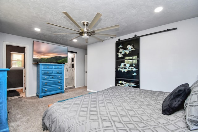 carpeted bedroom featuring ensuite bathroom, a barn door, a textured ceiling, and ceiling fan