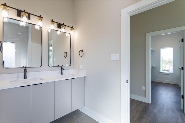 full bathroom with double vanity, a sink, and baseboards