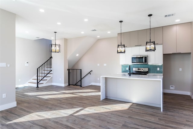 kitchen featuring light countertops, visible vents, appliances with stainless steel finishes, a kitchen island with sink, and modern cabinets