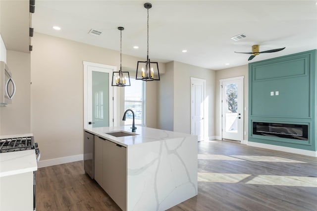 kitchen featuring a center island with sink, visible vents, stainless steel appliances, pendant lighting, and a sink