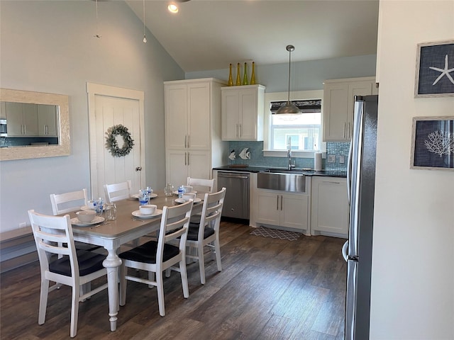 dining area featuring vaulted ceiling, sink, and dark hardwood / wood-style flooring