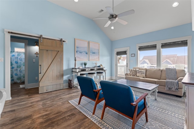 living room featuring hardwood / wood-style flooring, a barn door, high vaulted ceiling, and ceiling fan