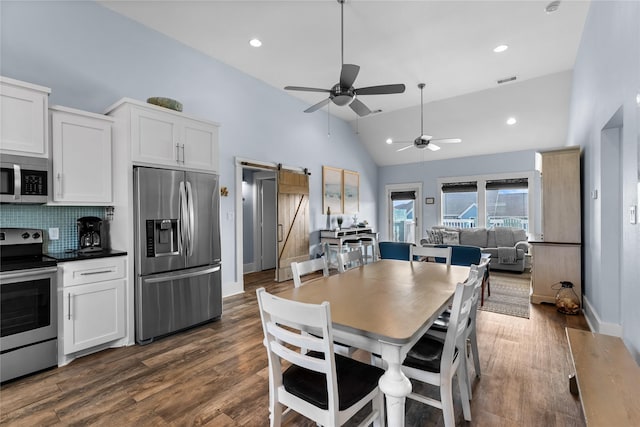 dining room with lofted ceiling, dark wood finished floors, ceiling fan, and a barn door