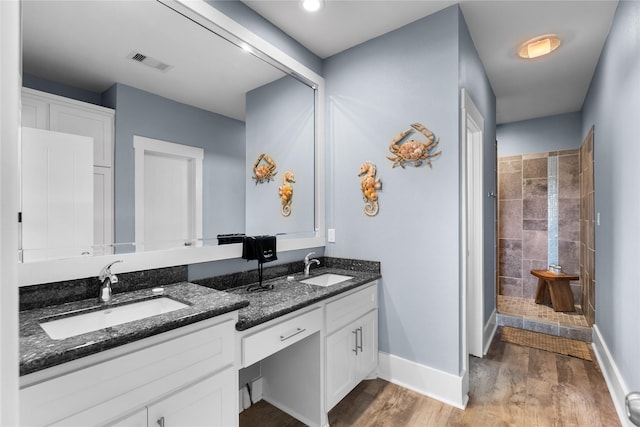 full bath featuring baseboards, visible vents, tiled shower, and a sink
